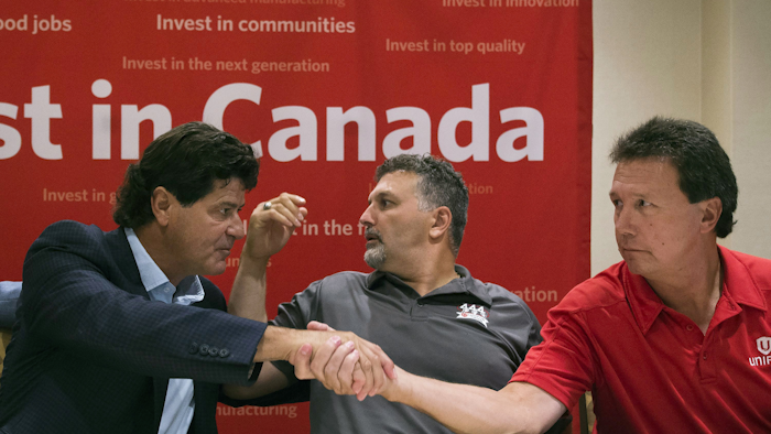 Unifor national president Jerry Dias, left, shakes hands with bargaining committee member Chris Taylor, right, of Ford Motor Company, as bargaining committee member Dino Chiodo, of Fiat Chrysler, sits between them, after the conclusion of a news conference regarding the ongoing Canadian Auto Workers union talks, Thursday, Aug. 11, 2016, in Toronto. (Nathan Denette/The Canadian Press via AP)