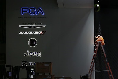 A worker prepares the Fiat Chrysler Automobiles area for the North American International Auto Show in Detroit. (AP Photo/Paul Sancya, File)