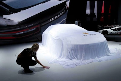 A worker adjusts the sheet around a car at the Porsche stand during the Paris Motor Show in Paris, France on Thursday, Sept. 29, 2016. (AP Photo/Michel Euler)