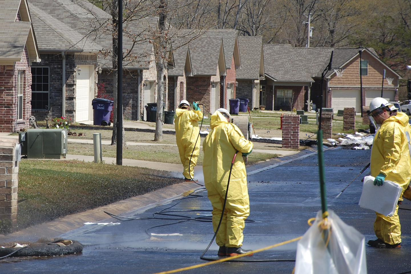 In this April 1, 2013 file photo, crews work to clean up oil in a Mayflower, Ark., neighborhood after an oil pipeline ruptured and spewed oil over lawns and roadways. Attorneys for landowners along the crude oil pipeline that ruptured in 2013 are asking a federal appeals court to reinstate their case. Landowners sued Exxon Mobil Pipeline Co., in 2013, alleging a breach of contract, but the case was dismissed in 2015. Oral arguments will be held Wednesday, Oct. 19, 2016, in Minnesota. (AP Photo/Jeannie Nuss, File)