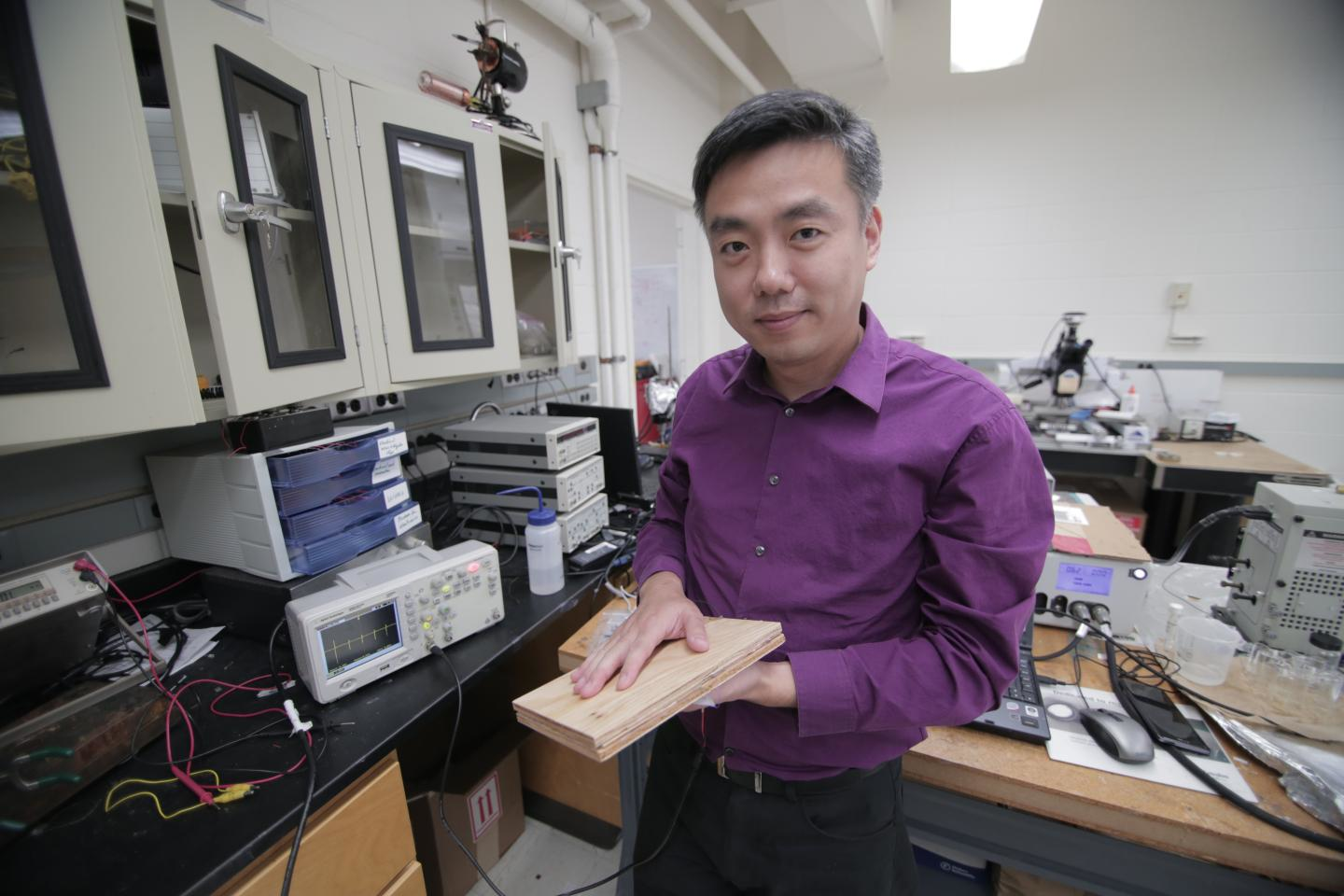 Associate Professor Xudong Wang holds a prototype of the researchers' energy harvesting technology, which uses wood pulp and harnesses nanofibers. The technology could be incorporated into flooring and convert footsteps on the flooring into usable electricity. (Stephanie Precourt/UW-Madison)