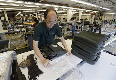 In this Wednesday, Aug. 31, 2016, photo, Ying Chau places a completed piece of luggage into a plastic bag at the C.C. Filson Co. manufacturing facility, in Seattle. On Monday, Oct. 3, 2016, the Institute for Supply Management, a trade group of purchasing managers, issues its index of manufacturing activity for September. (AP Photo/Ted S. Warren)