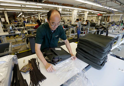 In this Wednesday, Aug. 31, 2016, photo, Ying Chau places a completed piece of luggage into a plastic bag at the C.C. Filson Co. manufacturing facility, in Seattle. On Monday, Oct. 3, 2016, the Institute for Supply Management, a trade group of purchasing managers, issues its index of manufacturing activity for September. (AP Photo/Ted S. Warren)
