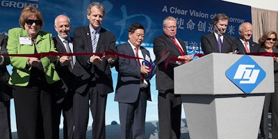 Cho Tak Wong, chairman of the Fuyao Group, center, cuts a ceremonial ribbon during the grand opening of the Fuyao Glass America plant, Friday, Oct. 7, 2016, in Moraine, Ohio. The Chinese company is ready to show off its completed automotive glass-making plant in Ohio, which serves as its North American hub for recycled glass manufacturing. (AP Photo/John Minchillo)
