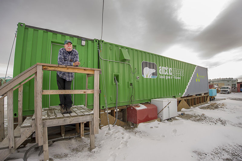 In this Oct. 26, 2016 photo provided by Will Anderson, employee Joe Carr stands outside a new indoor hydroponics farm owned by a local Alaska Native corporation in Kotzebue, Alaska. Arctic Greens is harvesting kale, various lettuces, basil and other greens weekly from the soil-free system and selling them at the supermarket in the community of nearly 3,300. (Will Anderson via AP)
