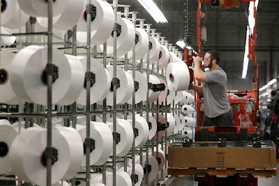 A worker loads spools of thread at the Repreve Bottle Processing Center, part of the Unifi textile company in Yadkinville, N.C., Friday, Oct. 21, 2016. America has lost more than 7 million factory jobs since manufacturing employment peaked in 1979. Yet American factory production, minus raw materials and some other costs, more than doubled over the same span to $1.91 trillion last year, according to the Commerce Department, which uses 2009 dollars to adjust for inflation. That’s a notch below the record set on the eve of the Great Recession in 2007. And it makes U.S. manufacturers No. 2 in the world behind China.. (AP Photo/Chuck Burton)