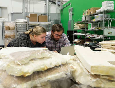 In this Tuesday, Sept. 27, 2016 photo, Ecovative Design co-founder Gavin McIntyre works with senior research biologist Lucy Greetham at Ecovative in Green Island, N.Y. Ecovative Design is a business staking its growth on mycelium, the thread-like 'roots' of mushrooms. The mycelium grows around small pieces of stalks and stems to create a bound-together material that can be molded into soft packaging for glassware or pressed into the boards used for the footstools they recently began selling. (AP Photo/Mike Groll)
