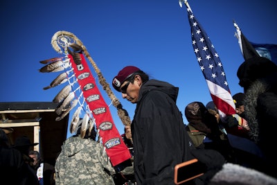 Native American veterans join an interfaith ceremony at the Oceti Sakowin camp where people have gathered to protest the Dakota Access oil pipeline in Cannon Ball, N.D., Sunday, Dec. 4, 2016. Tribal elders have asked the military veterans joining the large Dakota Access pipeline protest encampment not to have confrontations with law enforcement officials, an organizer with Veterans Stand for Standing Rock said Sunday, adding the group is there to help out those who've dug in against the four-state, $3.8 billion project. (AP Photo/David Goldman)
