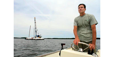 FILE - In this Monday, June 20, 2011, file photo Dr. Ray Konisky guides a barge loaded with tons of recycled surf clam shells through a narrow channel on Great Bay in Newmarket, N.H. A team of New Hampshire researchers is taking the first steps to developing a system that could alert the shellfish industry when a deadly pathogen is in the waters. The work of scientists at the University of New Hampshire and other institutions comes as the numbers of cases of people falling ill from eating raw oysters has spiked. (AP Photo/Jim Cole, File)