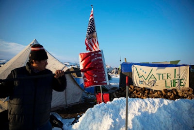 Benji Buffalo, a Grovan Native American from Montana, shovels snow outside his tent at the Oceti Sakowin camp where people have gathered to protest the Dakota Access oil pipeline in Cannon Ball, N.D., Saturday, Dec. 3, 2016. (AP Photo/David Goldman)