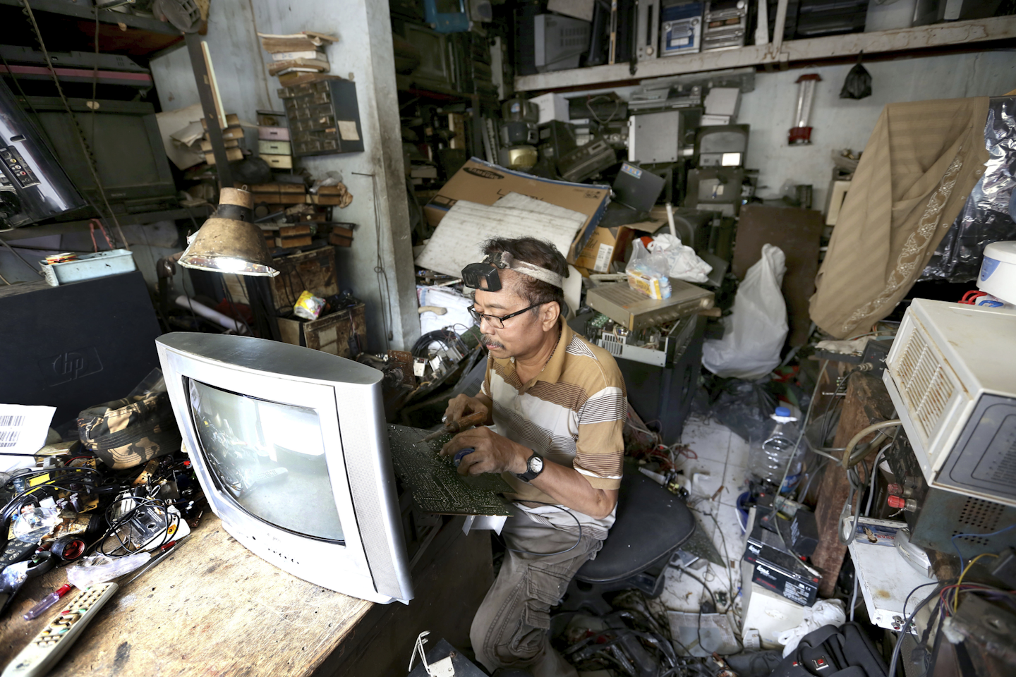 In this Thursday, Jan. 12, 2017, photo, a technician repairs an old television at his stall in Jakarta, Indonesia. The waste from discarded electronic gadgets and appliances has increased by two-thirds in East Asia over five years, posing a growing threat to health and the environment unless proper disposal becomes the norm. (AP Photo/Tatan Syuflana)