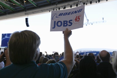 President Donald Trump speaks to Boeing employees, as one holds up a sign handed out by the company, Friday, Feb. 17, 2017, in the final assembly building at Boeing South Carolina in North Charleston, S.C. (AP Photo/Mic Smith)