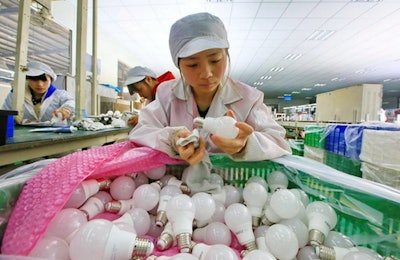A worker examines an LED light bulb at a factory in Suining city in southwestern China's Sichuan province. China’s factory activity picked up pace last month, surveys on Wednesday showed, adding to recent evidence that a key sector of the world’s No. 2 economy is stabilizing. (Chinatopix via AP)