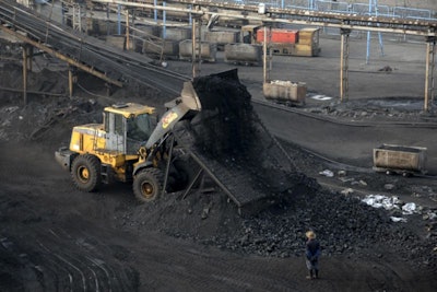 In this Monday, Feb. 20, 2017 photo, a worker watches a bulldozer unload coal at a coal mine in Huaibei in central China's Anhui province. (Chinatopix via AP)
