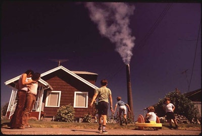 Children play in yard of Ruston Home, while Tacoma smelter stack showers area with arsenic and lead residue in 1972. (Image credit: Gene Daniels, NARA)