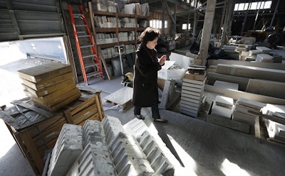 In this Feb. 14, 2017, photo, Teresa Van Vleet-Danos walks through the production area in the Rowat Cut Stone & Marble plant in Des Moines, Iowa. Manufacturing businesses across the country are getting pushed out of neighborhoods where they have operated for decades as cities remake gritty industrial districts into trendy hotspots. Due to encroaching development, Rowat Cut Stone & Marble has until this summer to clear out, leaving behind a weathered building that will be knocked down and replaced with apartment towers. (Charlie Neibergall/Associated Press)
