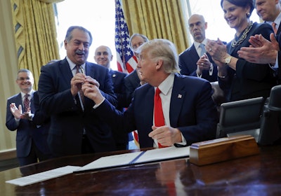 In this Feb. 24, 2017, file photo, President Donald Trump gives the pen he used to sign an executive order to Dow Chemical President, Chairman and CEO Andrew Liveris, as other business leaders applaud in the Oval Office of the White House in Washington. Dow Chemical is pushing the Trump administration to scrap the findings of federal scientists who point to a family of widely used pesticides as harmful to about 1,800 critically threatened or endangered species. Liveris is a close adviser to President Donald Trump. The company gave $1 million for Trump’s inaugural activities.(AP Photo/Pablo Martinez Monsivais, File)