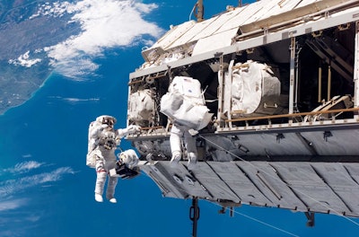 In this Dec. 12, 2006 photo made available by NASA, astronaut Robert L. Curbeam Jr., left, and European Space Agency astronaut Christer Fuglesang, participate in a spacewalk during construction of the International Space Station. In the background are New Zealand and the Pacific Ocean. According to a report released Wednesday, April 26, 2017, NASA is managing a variety of design and health risks associated with the spacewalking suits used by astronauts aboard the International Space Station. The suits were developed more than 40 years ago and intended for only 15 years' use. (NASA via AP)