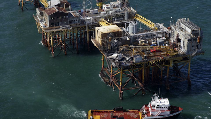 In this aerial photograph, a supply vessel moves near an oil rig damaged by an explosion and fire, Friday, Nov. 16, 2012, in the Gulf of Mexico about 25 miles southeast of Grand Isle, La. (AP Photo/Gerald Herbert)