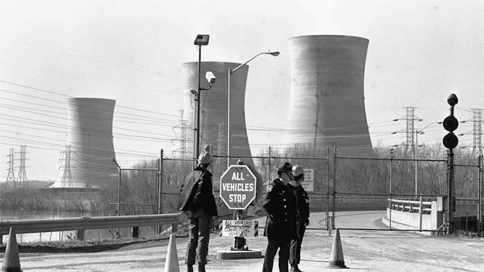 In this undated file photo, a Pennsylvania state police officer and plant security guards stand outside the closed front gate to the Metropolitan Edison nuclear power plant on Three Mile Island near Harrisburg, Pa., after the plant was shut down following a partial meltdown on March 28, 1979. (Image credit: Paul Vathis via AP)