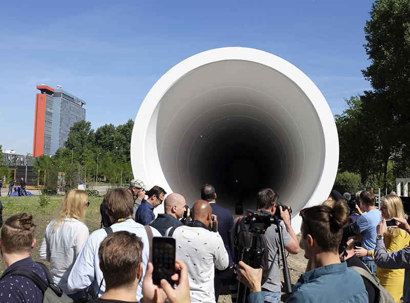 People look at a hyperloop test facility unveiled by a tech startup and a construction company in Delft, Netherlands, Thursday, June 1, 2017. The 30 meter (100 foot) long white steel tube will be used to help develop the futuristic high-speed transportation system. The tube is a first step toward developing the system in the Netherlands, a key European transportation transport hub. (AP Photo/Mike Corder)