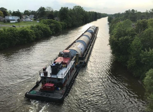 In this undated photo, a barge carrying Chinese-made beer fermentation tanks floats down the Erie Canal in Clyde, N.Y., toward the Genesee Brewery in Rochester, N.Y. Some politicians are irritated that the Rochester brewery, which receives state economic development funding, bought beer fermentation tanks from China that could have been produced in New York. (Michael Riviello via AP)