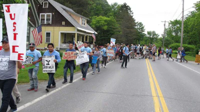Scores of dairy farm workers and activists marching in Montpelier, Vt., on Saturday June, 17, 2017. They were marching to the main Ben & Jerry's factory in the Vermont town of Waterbury to protest what they feel are slow negotiations to reach a deal on their 'Milk with Dignity' program that would ensure fair wages and living conditions. Ben & Jerry's spokesman Sean Greenwood says the company is committed to reaching a deal with workers. (AP Photo/Wilson Ring)