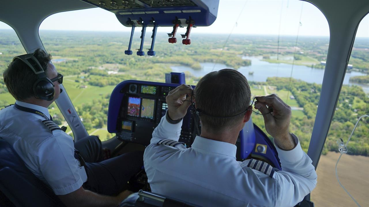 In this Monday, May 15, 2017, photo, Michael Doughtery, right, chief Goodyear pilot, lifts his earpiece off during an airship training flight for William Bayliss, left, over Akron, Ohio. The Goodyear Tire company is training pilots of its iconic blimps to fly new airships in northeast Ohio. Goodyear retired the last of its old blimp fleet in March. (AP Photo/Dake Kang)