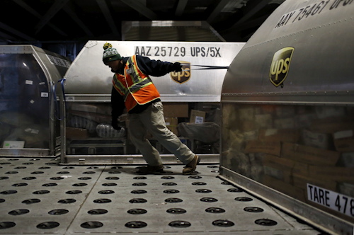 A UPS worker pulls a container full of packages across a floor of embedded casters in the UPS Worldport facility in Louisville, Kentucky. (AP Photo/Patrick Semansky)