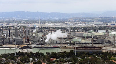 Standard Oil Refinery in El Segundo, Calif., with Los Angeles International Airport in the background and the El Porto neighborhood of Manhattan Beach, Calif., in the foreground. A plan to extend California's cap-and-trade program for another decade looks beyond cutting greenhouse gas emissions and takes aim at toxic air in the polluted neighborhoods around refineries and factories. (AP Photo/Reed Saxon, File)