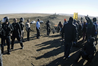 In this Nov. 11, 2016, file photo, law enforcement try to move Dakota Access pipeline protesters further down during a protest at a pipeline construction site south of St. Anthony, N.D. The Trump administration has denied a request from Republican North Dakota Gov. Doug Burgum for a 'major disaster declaration' to help cover some of the estimated $38 million cost to police protests of the pipeline. (Mike McCleary/The Bismarck Tribune via AP, File)