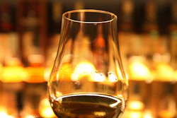 FILE- In this March 10, 2013 file photo, a glass of whisky is held up in front of the Diageo Claive Scotch Whisky collection in Edinburgh, Scotland. Scotland has called for Scotch to be defined in U.K. law so that the whisky industry can be protected after Brexit. (David Cheskin/PA via AP, file)