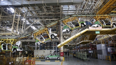 A line of Peugeot 206, containing its hatchback and sedan, is on the production line at the state-run Iran-Khodro automobile manufacturing plant near Tehran, Iran, Saturday, Oct. 11, 2014. (AP Photo)