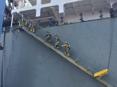 This photo courtesy of the Long Beach Fire Department shows firefighters boarding a ship responding to an hazmat incident in the Port of Long Beach, Calif., Sunday, Aug. 6, 2017. Long Beach firefighters treated 11 workers and one firefighter for exposure to some hazardous material fumes, at Pier G, where a flammable liquid leaked from a 6,000 gallon tank on a container vessel. Two persons have been taken to a hospital. (Brian Fisk/Long Beach Fire Department via AP)