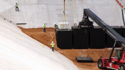 In this June 6, 2013 file photo, crews from Waste Control Specialists load the first of two containers with low-level radioactive waste from Los Alamos National Laboratory in New Mexico, into a reinforced 8-inch-thick concrete container at the 90-acre federal dump where it will remain forever, near Andrews, Texas. (AP Photo/Betsy Blaney)