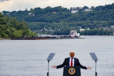 A coal barge is positioned as a backdrop behind President Donald Trump as he speaks during a rally at the Rivertowne Marina in Cincinnati. President Donald Trump personally promised to activate emergency legal authorities to keep dirty or economically uncompetitive coal plants from shutting down, a top American coal company said. The Trump administration now says it has no plans to do so. (AP Photo/John Minchillo, File)