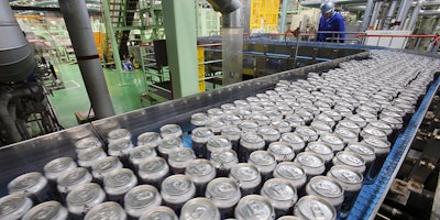 In this Monday, May 29, 2017 photo, an Asahi Breweries employee checks the beer production line at a factory in Moriya near Tokyo. Thousands upon thousands of cans are getting filled with beer, capped, washed, then wrapped into a six-pack and boxed at dizzying speeds - 1,500 a minute - on humming conveyor belts that zip and wind in this sprawling factory. (AP Photo/Koji Sasahara)