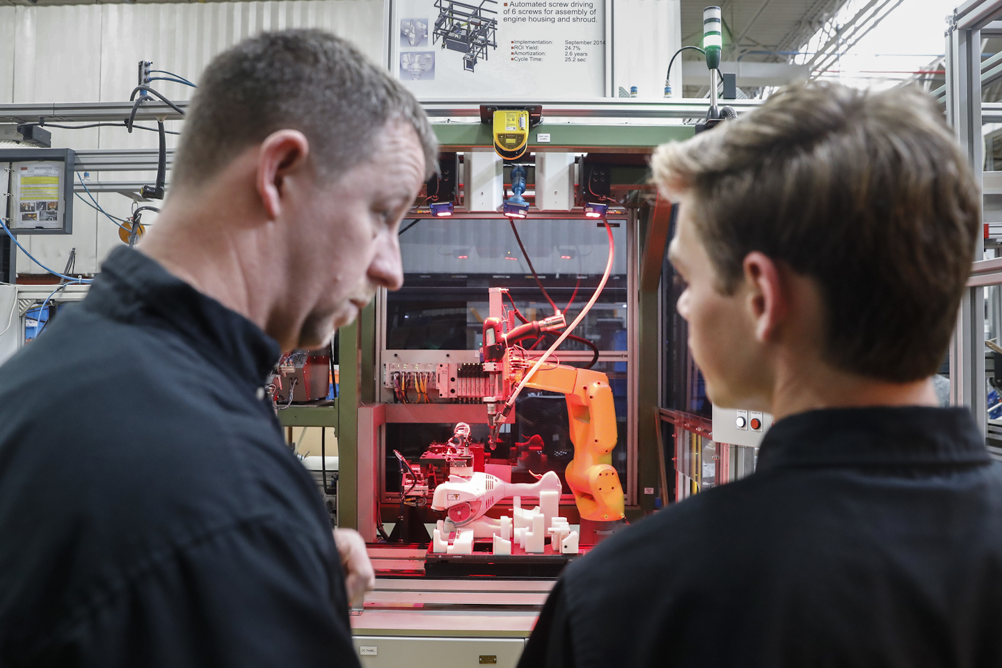 In this Thursday, May 25, 2017 photo, A.J. Scherman, 37, left, works with fellow apprentice Ryan Buzzy, 18, right, on a robotics control computer at a chainsaw assembly line at a Stihl Inc. production plant in Virginia Beach, Va. Scherman, with only a high-school degree, wanted to earn more money when his daughter was born and took a chance with a mid-life career change. Scherman is earning a college degree as part of a Stihl apprenticeship and will finish debt-free thanks to financial aid provided by the company. 'We're safe, because we're the guys who fix the robots when they malfunction,' Sherman said. 'We're going to need people to fix the more advanced systems. This program trains us.' (AP Photo/John Minchillo)
