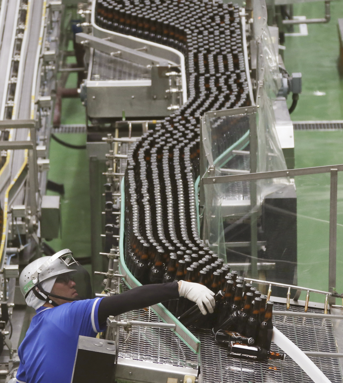 In this Monday, May 29, 2017 photo, an Asahi Breweries employee works on the production line at a factory in Moriya near Tokyo. Japan is ahead of the U.S. and Europe in introducing robots to the workplace, but that has not resulted in the job reductions in routine mid-level employment observed in other nations. (AP Photo/Koji Sasahara)