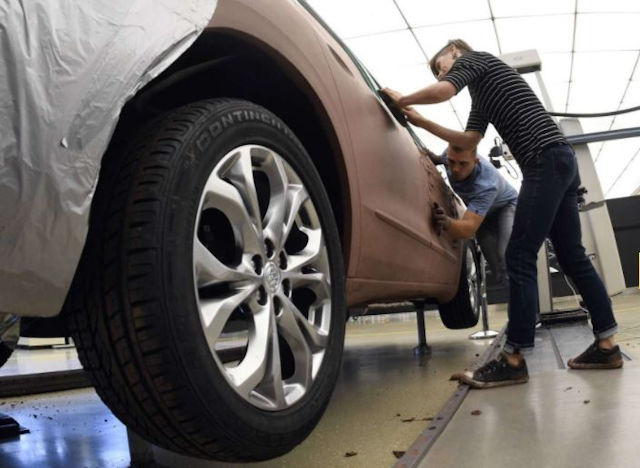 GM clay sculptors pack clay into a model of a 2018 Buick Enclave at the GM Tech Center in Warren, Mich. (AP Photo/Jose Juarez)