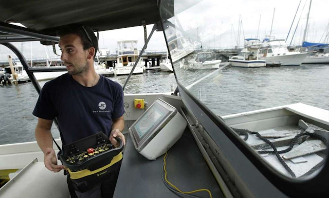 Sea Machines Robotics engineer Frank Marino uses a remote control belt pack to control a self-driving boat (AP photo)