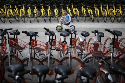 A child rides past bicycles from bike-sharing companies parked along a sidewalk in Beijing. A report says China’s factory activity expanded in September at the fastest pace in five years, indicating a healthy outlook for the world’s second-biggest economy. (AP Photo/Andy Wong, File)