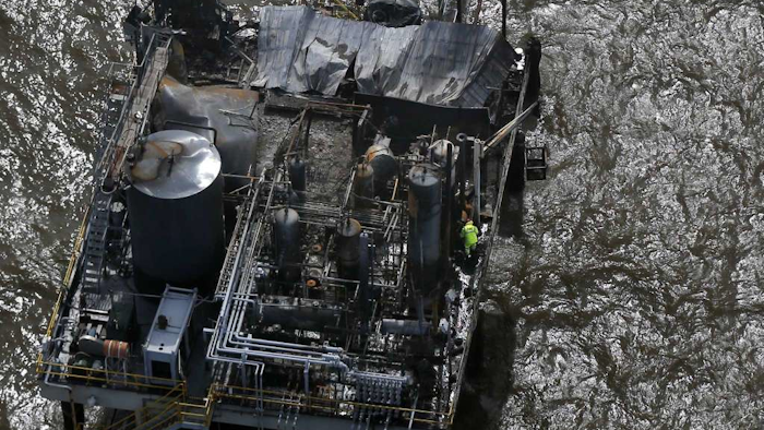 A worker stands on an oil and gas platform in Lake Pontchartrain in Kenner, La., that exploded overnight near New Orleans, Monday, Oct. 16, 2017. Seven people were injured, including three who were in critical condition, authorities said. Authorities searched by air and water Monday for a contractor who disappeared in the blast. (AP Photo/Gerald Herbert)