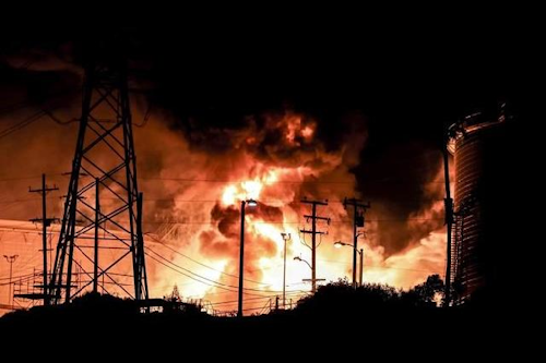 In this Tuesday, Oct. 17, 2017, photo provided by Jack Zellweger, a fire rages at the Chevron El Segundo Refinery in El Segundo, Calif. A fire that erupted at the West Coast's largest oil refinery threatened storage tanks and sent huge flames into the sky and black smoke across neighborhoods before crews quickly smothered it. Dozens of firefighters responded late Tuesday to the 1,000-acre refinery just south of Los Angeles, which processes nearly 275,000 gallons of crude per day. (Jack Zellweger via AP)