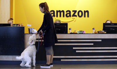 An Amazon employee gives her dog a biscuit as the pair head into a company building, where dogs are welcome, in Seattle. Amazon says it received 238 proposals from cities and regions hoping to be the home of the company's second headquarters. The online retailer kicked off its hunt for a second headquarters in September, promising to bring 50,000 new jobs. It will announce a decision sometime in 2018. (AP Photo/Elaine Thompson, File)