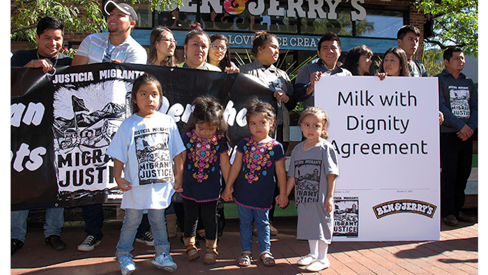Children stand in front of a banner commemorating an agreement signed by ice cream maker Ben & Jerry's and immigrant farm workers, Tuesday, Oct. 3, 2017, in Burlington, Vt. The agreement promotes the rights of immigrant farm workers while paying more to the farmers who employ them. The company and the workers said it's the first agreement of its kind in the dairy industry. (AP Photo/Wilson Ring)