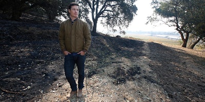 Adam Mariani poses in a burned area of the Scribe Winery, Wednesday, Oct. 18, 2017, in Sonoma, Calif. The winery was almost destroyed by the fire, but Mariani, along with family members and employees, worked through the night, to keep it from burning. The deadliest and most destructive wildfires in California history imperiled both the low-wage workers who harvest the nation's most valuable wine grapes and the wealthy entrepreneurs who employ them. (AP Photo/Rich Pedroncelli)