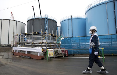 In this Feb. 23, 2017, file photo, an employee walks past storage tanks for contaminated water at the tsunami-crippled Fukushima Dai-ichi nuclear power plant of the Tokyo Electric Power Co. (TEPCO) in Okuma town, Fukushima prefecture, Japan. More than six years after a tsunami overwhelmed the Fukushima nuclear power plant, Japan has yet to reach consensus on what to do with a million tons of radioactive water, stored on site in around 900 large and densely packed tanks that could spill should another major earthquake or tsunami strike. (Tomohiro Ohsumi/Pool Photo via AP, File)