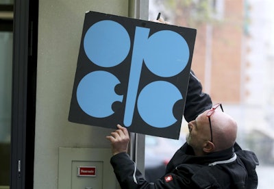 A worker attaches a poster of the Organization of the Petroleum Exporting Countries, OPEC, at their headquarters in Vienna, Austria, Wednesday, Nov. 29, 2017. With bills rising for gasoline or heating oil, consumers around the world are paying the price for a decision by OPEC and Russia last year to cut production. The strategy is working for those oil-producing nations and will likely be extended at a meeting Thursday. (AP Photo/Ronald Zak)