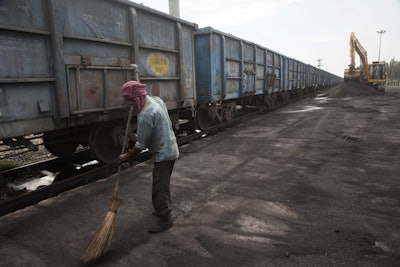 In this July 14, 2017 photo, Baburam sweeps domestically produced petroleum coke to be transported onto trucks hired by local factories in Rampur about 210 kilometers (130 miles) from New Delhi, India. The petcoke being burned in countless factories and plants is contributing to dangerously filthy air in India, which already has many of the world’s most polluted cities. India’s energy-hungry industries like petcoke because it’s cheaper and burns hotter than coal; they also defend their use by saying they’re recycling a waste that’s being produced anyway. (AP Photo/Vaishnavee Sharma)
